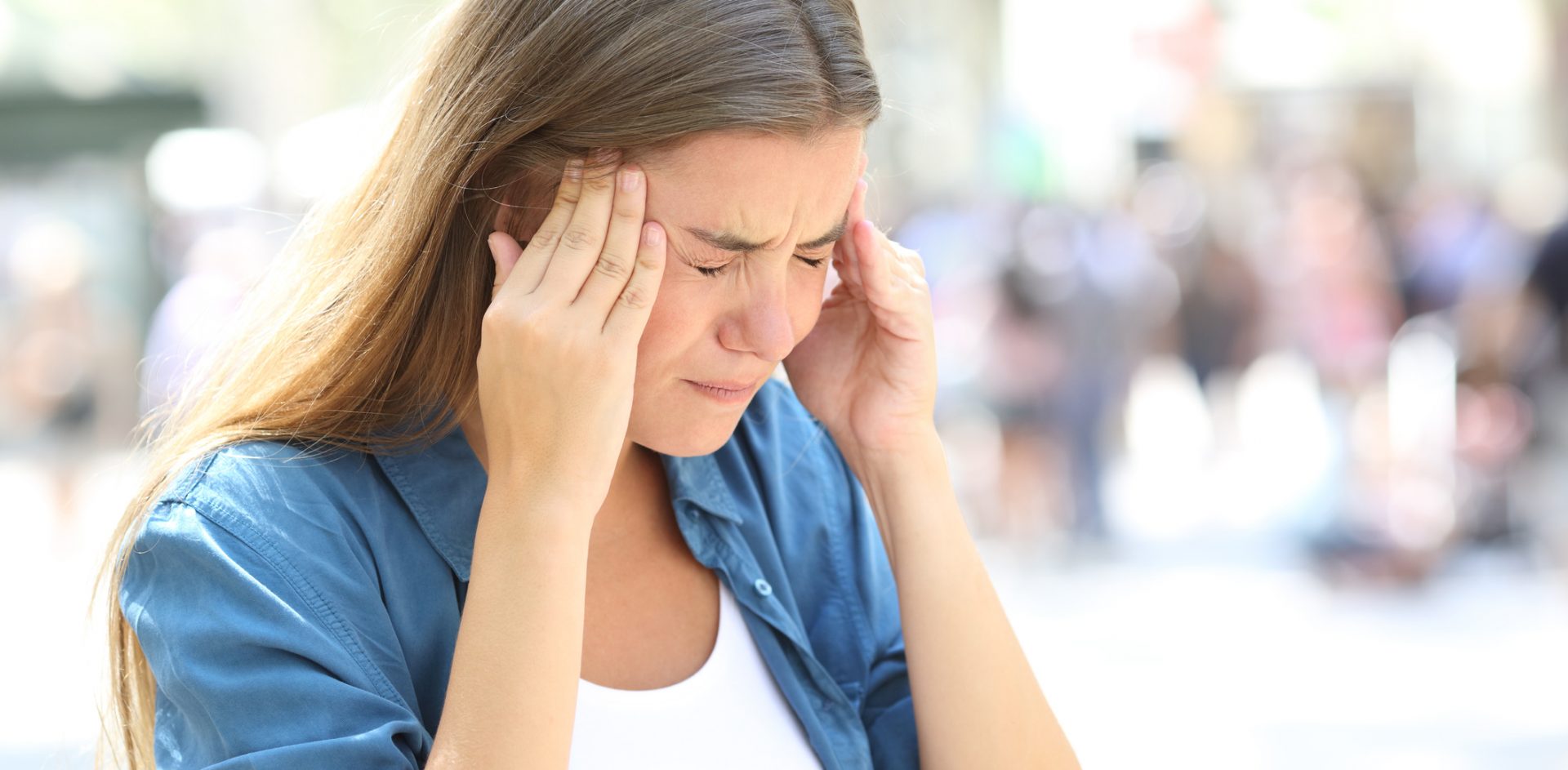 Painful girl suffering migraine touching temple in the street