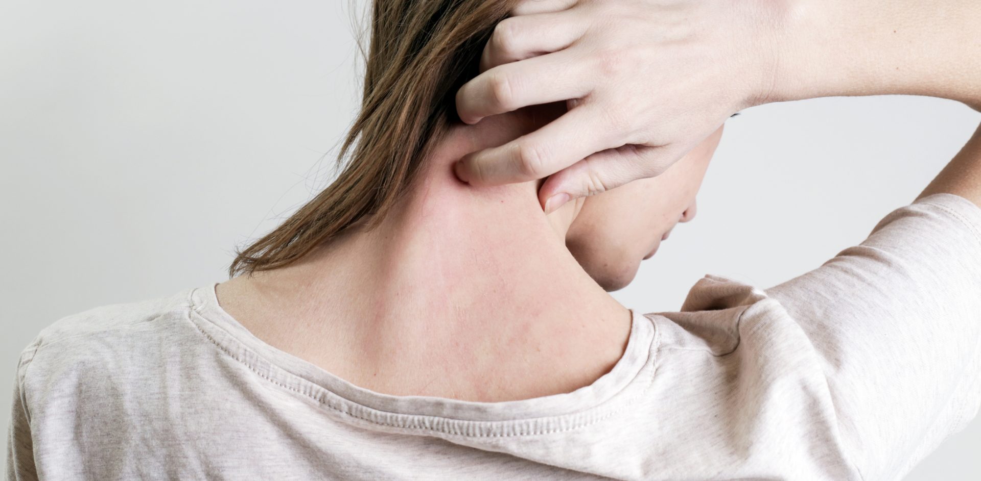 Close up view of woman scratching her neck.